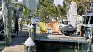 Un muelle de madera que conduce a una marina, rodeado de edificios residenciales y palmeras.