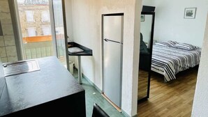 Habitación pequeña con kitchenette, una cama y vistas a través de un arco.