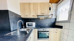 Una cocina moderna con un lavamanos, microondas, horno y armarios de madera.