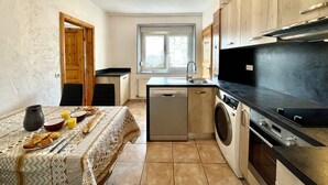 Une cuisine compacte équipée d’un lave-vaisselle, d’un lave-linge et d’un coin repas avec une table dressée pour deux personnes.