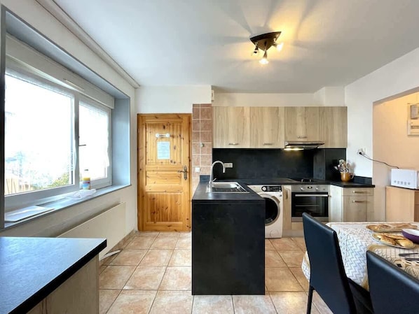 A modern kitchen with a central island, built-in oven, and a dining area with a table and chairs.