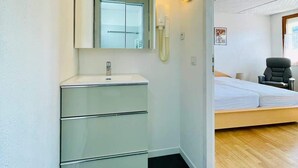 A modern bathroom with a mirror, sink, and toilet. - Angèle (Bains-les-Bains)