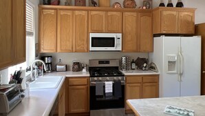 A kitchen with wooden cabinets, a stainless steel stove, a microwave, and a refrigerator. - Rural home wheelchair accessible, pet friendly close to River & lake & I-80. (Meadow Vista)