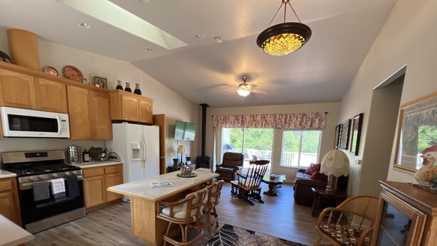 A spacious kitchen with wooden cabinets, a central island, and a dining area with chairs. - Rural home wheelchair accessible, pet friendly close to River & lake & I-80. (Meadow Vista)