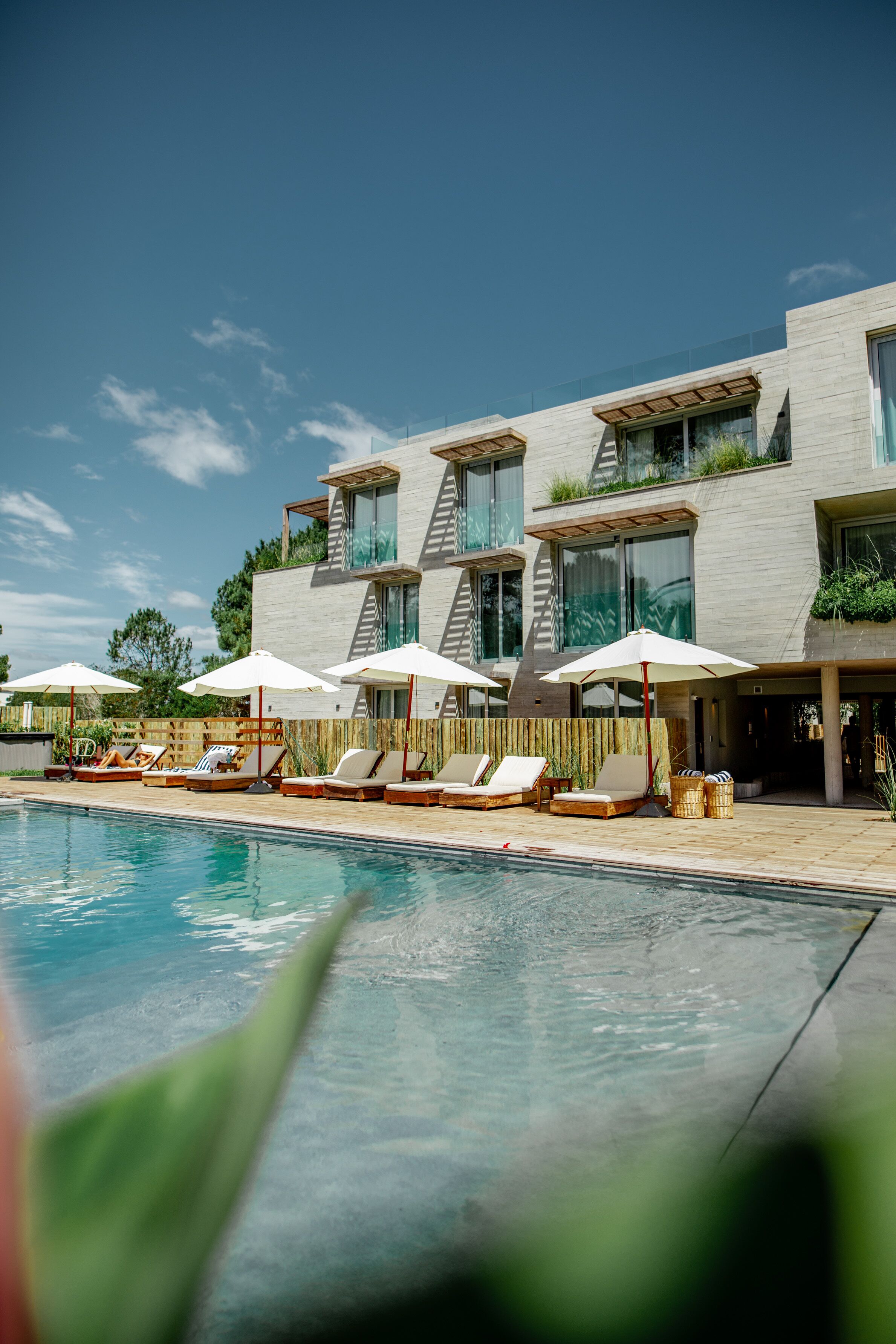 Un hotel moderno con piscina, tumbonas y sombrillas.