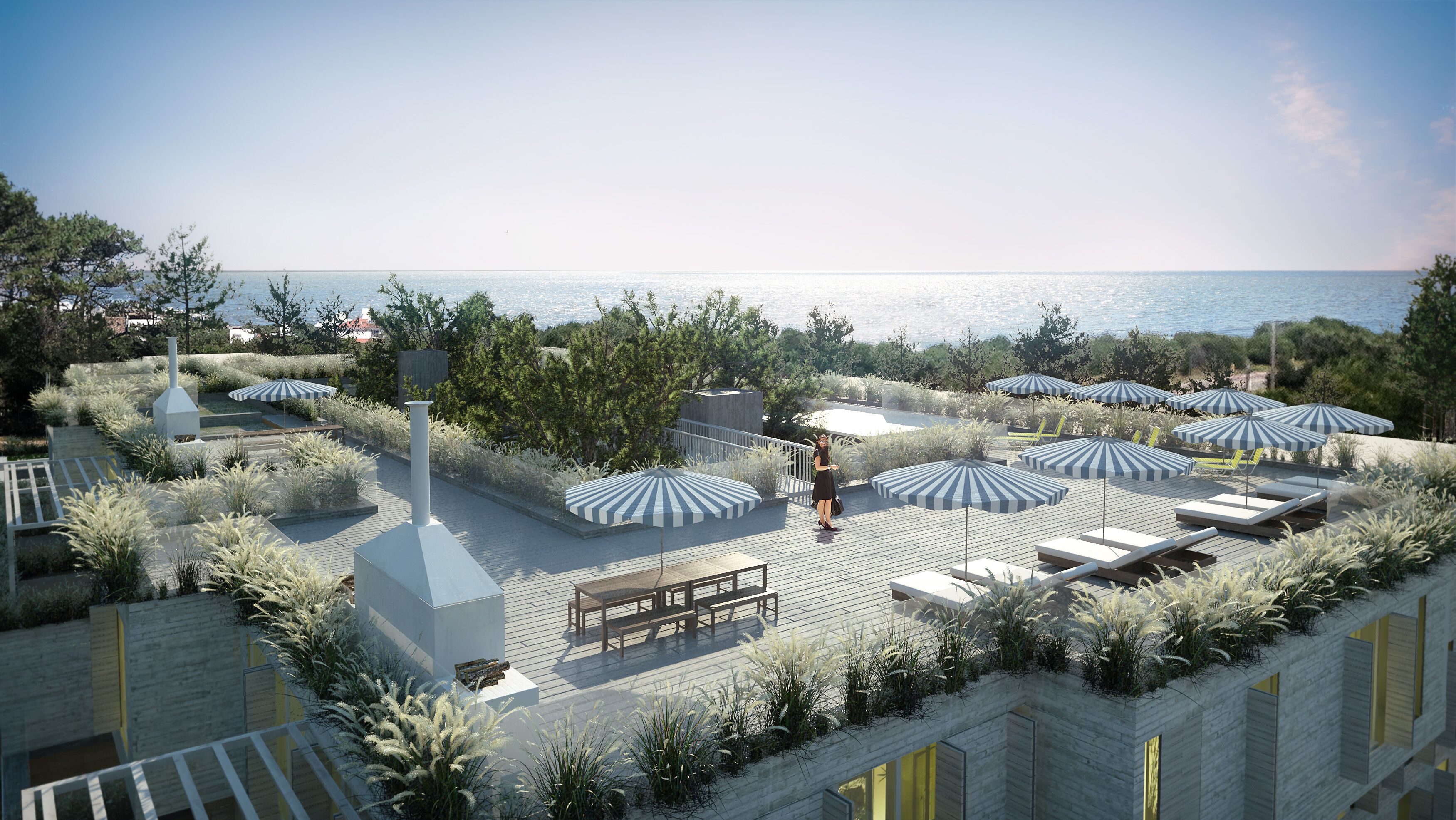 Terraço costeiro com cadeiras de descanso, guarda-sóis e vista para o mar.