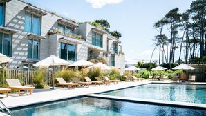 Hotel modern amb zona de piscina, gandules i ombrelles.