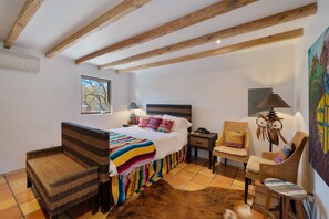 A bedroom with a bed, two wicker chairs, a small table, a lamp, and a painting. - Dancing Hare - Colorful and Inviting Tesuque Home Right Next to Bishop`s Lodge (Santa Fe)