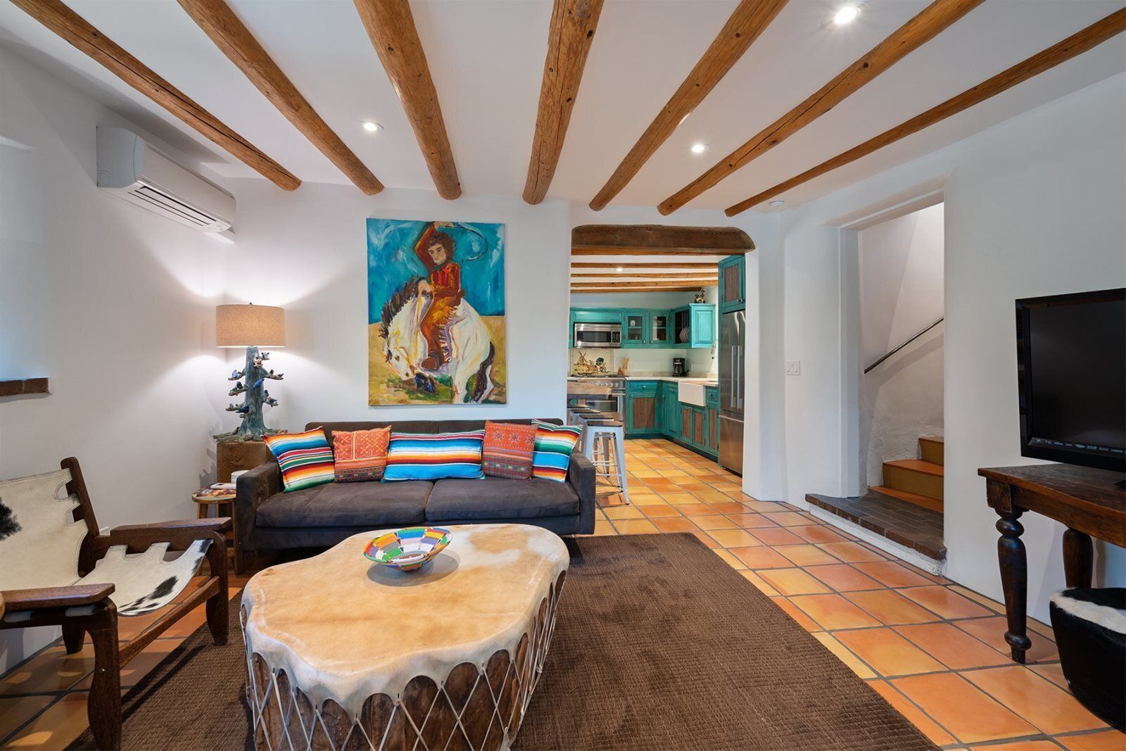 Uma sala de estar com um sofá, uma mesa de centro e um quadro na parede.