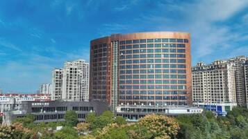 A modern high-rise building with a curved facade, surrounded by other high-rise buildings and greenery.