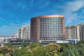 Un immeuble moderne de grande hauteur, doté d’une façade incurvée, entouré d’autres immeubles de grande hauteur et de verdure.