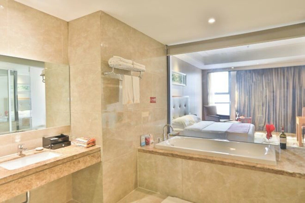 Un baño moderno con un espejo grande, un lavamanos y una bañera.
