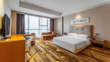 Una habitación de hotel con una cama grande, un escritorio, una silla y un televisor.