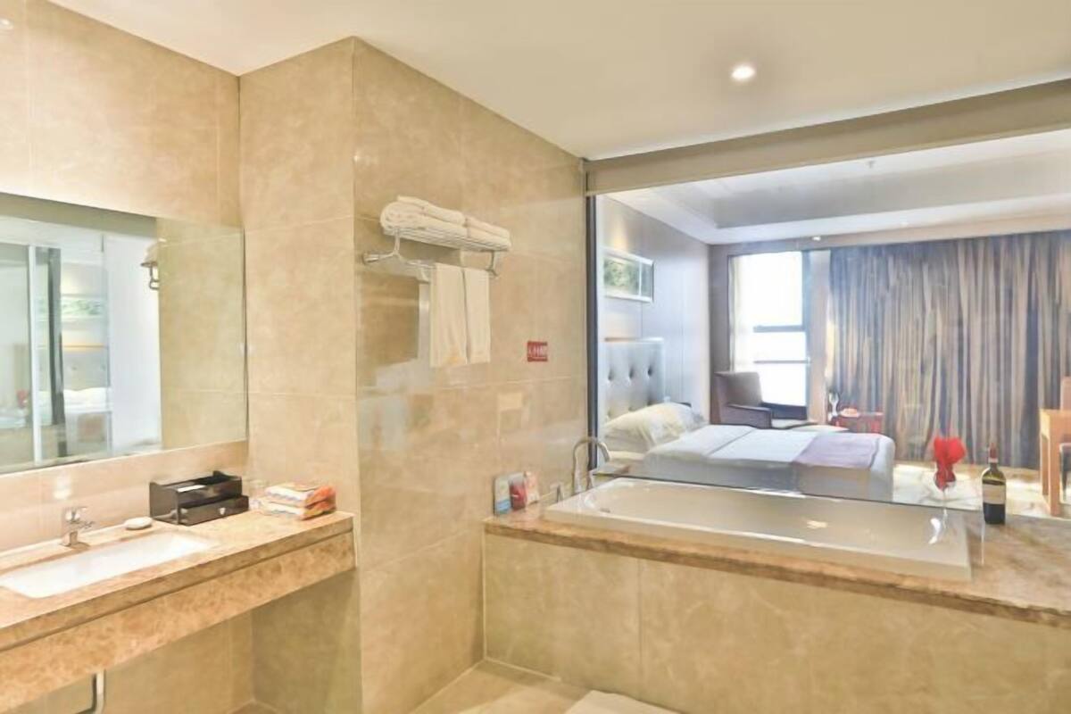 A modern bathroom with a large mirror, a bathtub, and a vanity with a sink.