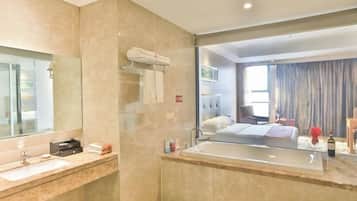Un baño moderno con un espejo grande, una bañera y un tocador con lavabo.