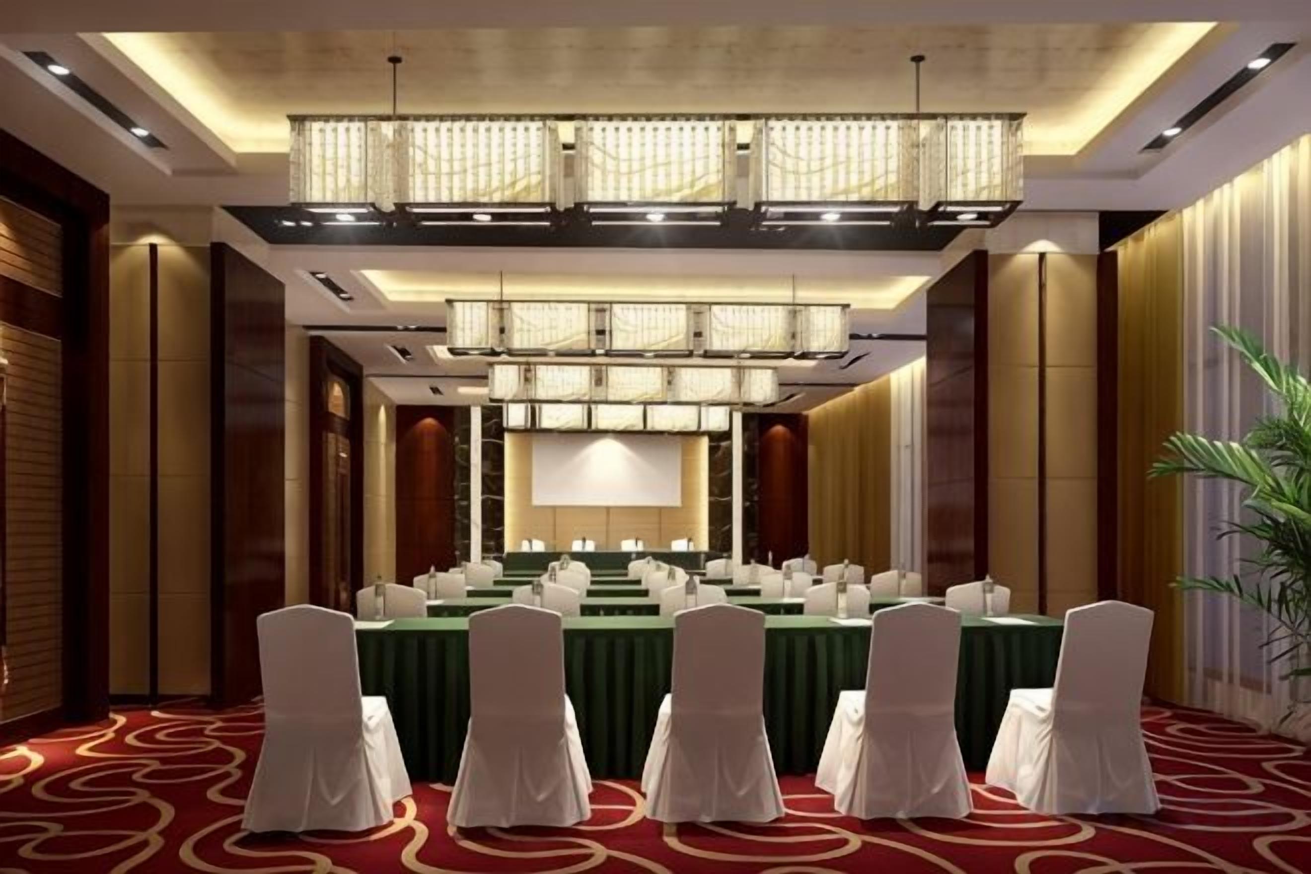 A conference room with a long table, chairs, and a large screen.