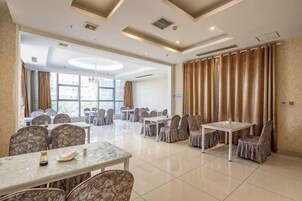 Un salón de conferencias de hotel con varias mesas y sillas, ventanas amplias y un diseño moderno del techo.