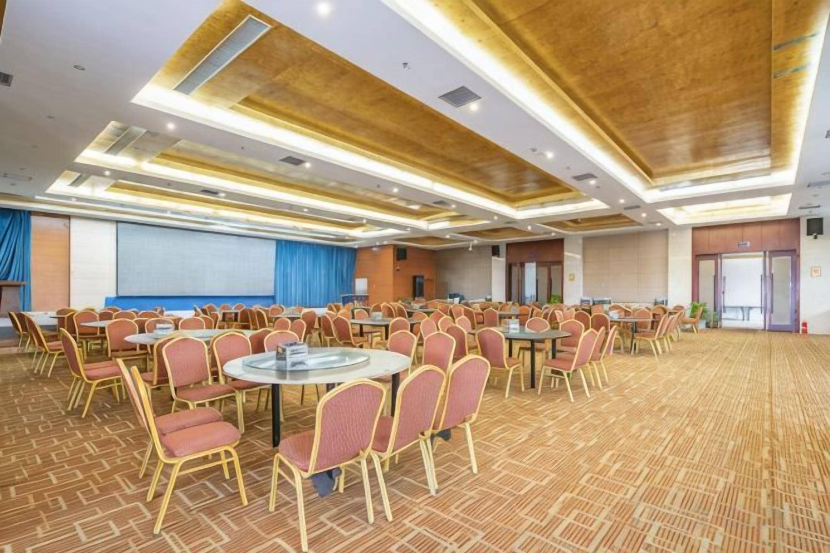 A conference room with round tables and chairs, a projector screen, and a carpeted floor.