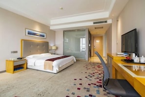 Una habitación de hotel con cama, mesita de noche, televisor y escritorio con silla.