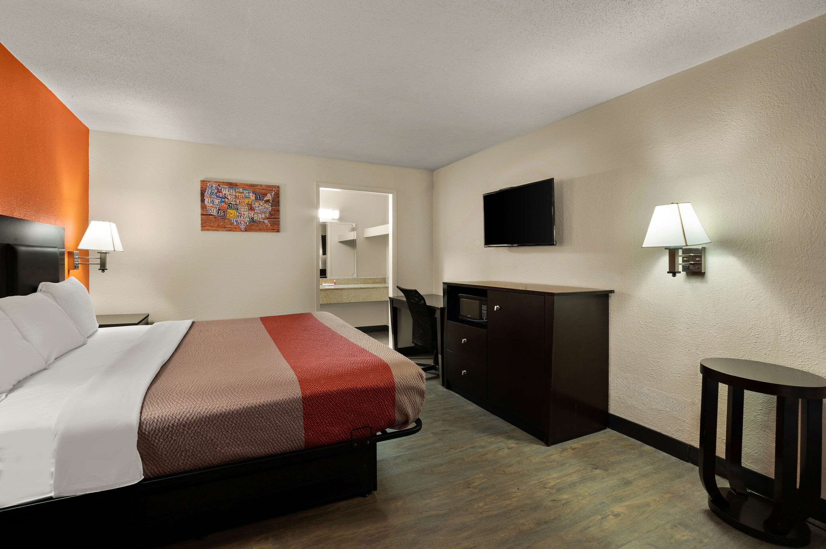 Une chambre d’hôtel avec un lit, un bureau, une chaise, une télévision et une petite table.
