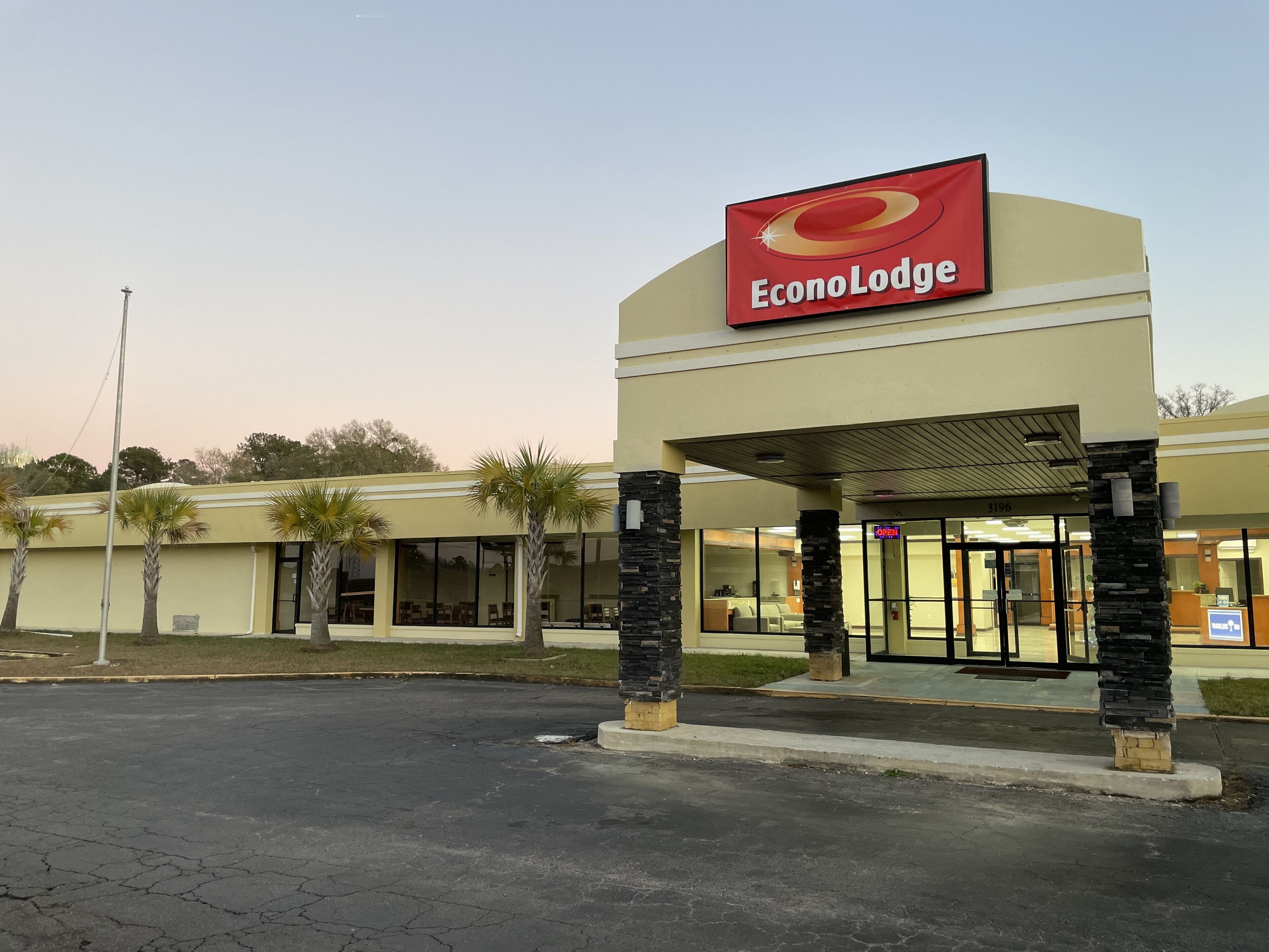 Edificio di un EconoLodge con un grande cartello, un parcheggio e palme.