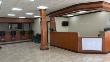 A reception area with a curved wooden desk, a flat-screen TV, and a seating area with chairs.