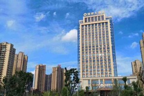 A high-rise hotel with multiple floors, a prominent entrance, and a clear sky. - Ruixiang Hotel (Fushun)