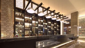 A modern bar area with a marble counter, shelves of bottles, and pendant lighting. - Ruixiang Hotel (Fushun)