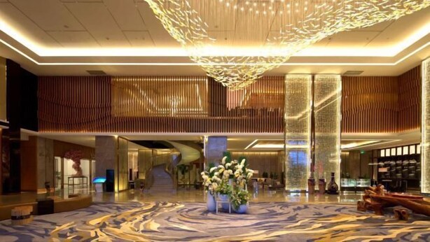 A spacious lobby with a modern chandelier, a central floral arrangement, and a patterned carpet. - Ruixiang Hotel (Fushun)
