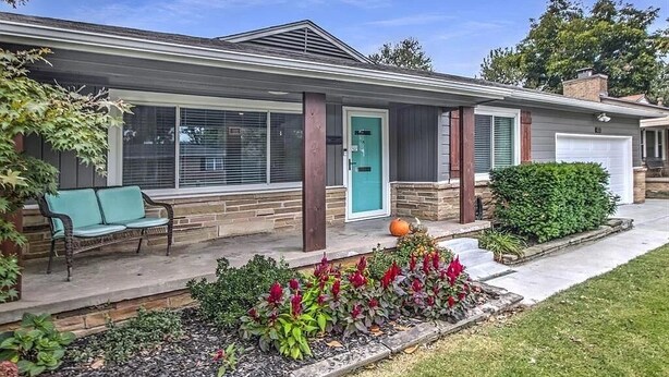 A single-story house with a front porch, a green door, and a garage.
