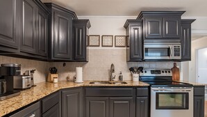 A kitchen with dark cabinetry, a stainless steel range, and a microwave above the stove.