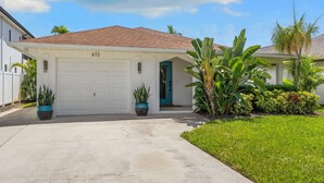 A residential house with a garage, numbered 672, and a well-maintained lawn with tropical plants. - 672 Casa Palmera - 3BD Heated Pool Home-Mins2Beach (Naples)