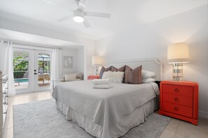 A bedroom with a bed, bedside tables, a red dresser, and a ceiling fan.