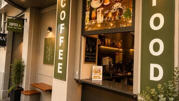 Un café avec un tableau affichant le menu, une enseigne représentant une tasse de café et une autre indiquant les plats proposés.