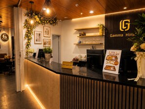 En hotellobby med en receptionsdisk, en skylt med namnet Gamma Hotel och ett specialerbjudande med ett förmånligt paketpris.