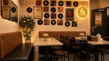A restaurant interior with a wall of vinyl records, a neon sign, and a seating area with tables and chairs.