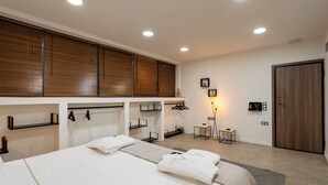 Una habitación de hotel con una cama grande, un escritorio, una silla, un armario y una mesita de noche con una lámpara.