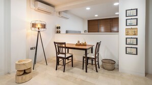 Un comedor con una mesa y sillas de madera, una lámpara de pie y obras de arte en la pared.