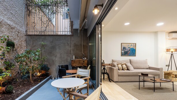 Un espacio moderno con sala de estar, sofá, mesa de centro y comedor, un balcón con plantas y un cuadro en la pared.