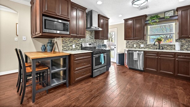 A modern kitchen with wooden cabinets, a stainless steel microwave, and a built-in oven.
