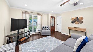 A living room with a flat-screen TV, a ceiling fan, a sofa, and a coffee table.