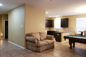 Relax in this stylish living room with a sofa, kitchen area, and pool table.