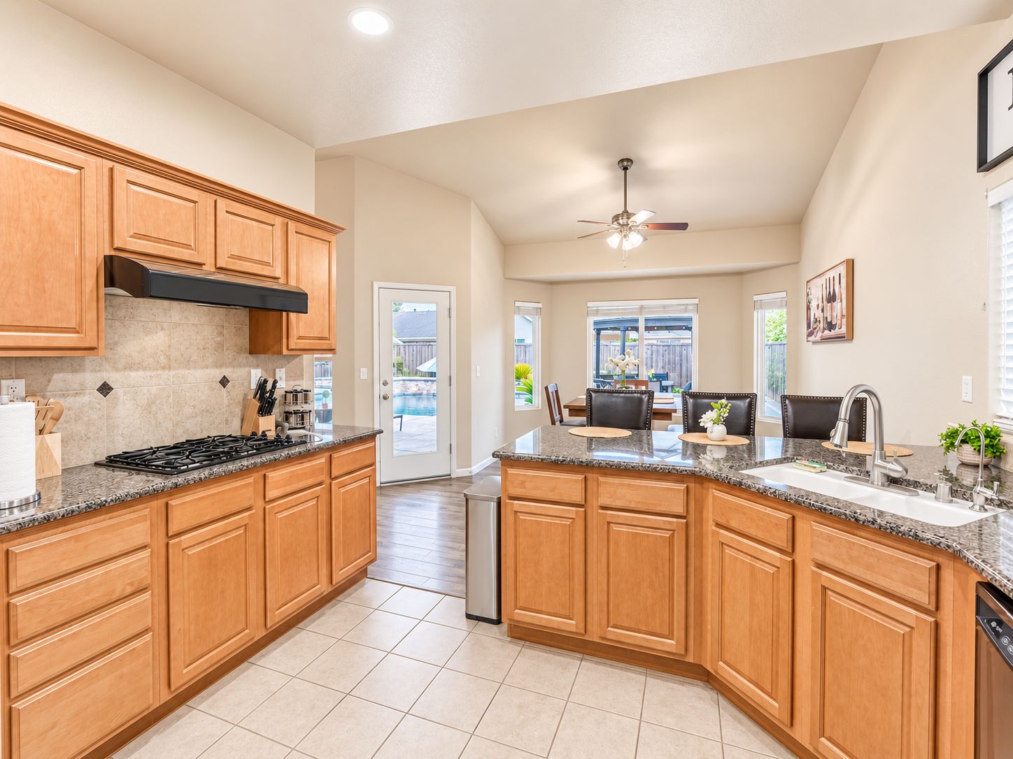 A spacious kitchen with granite countertops, wooden cabinets, and a built-in dishwasher.