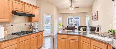 A spacious kitchen with granite countertops, wooden cabinets, and a built-in dishwasher.