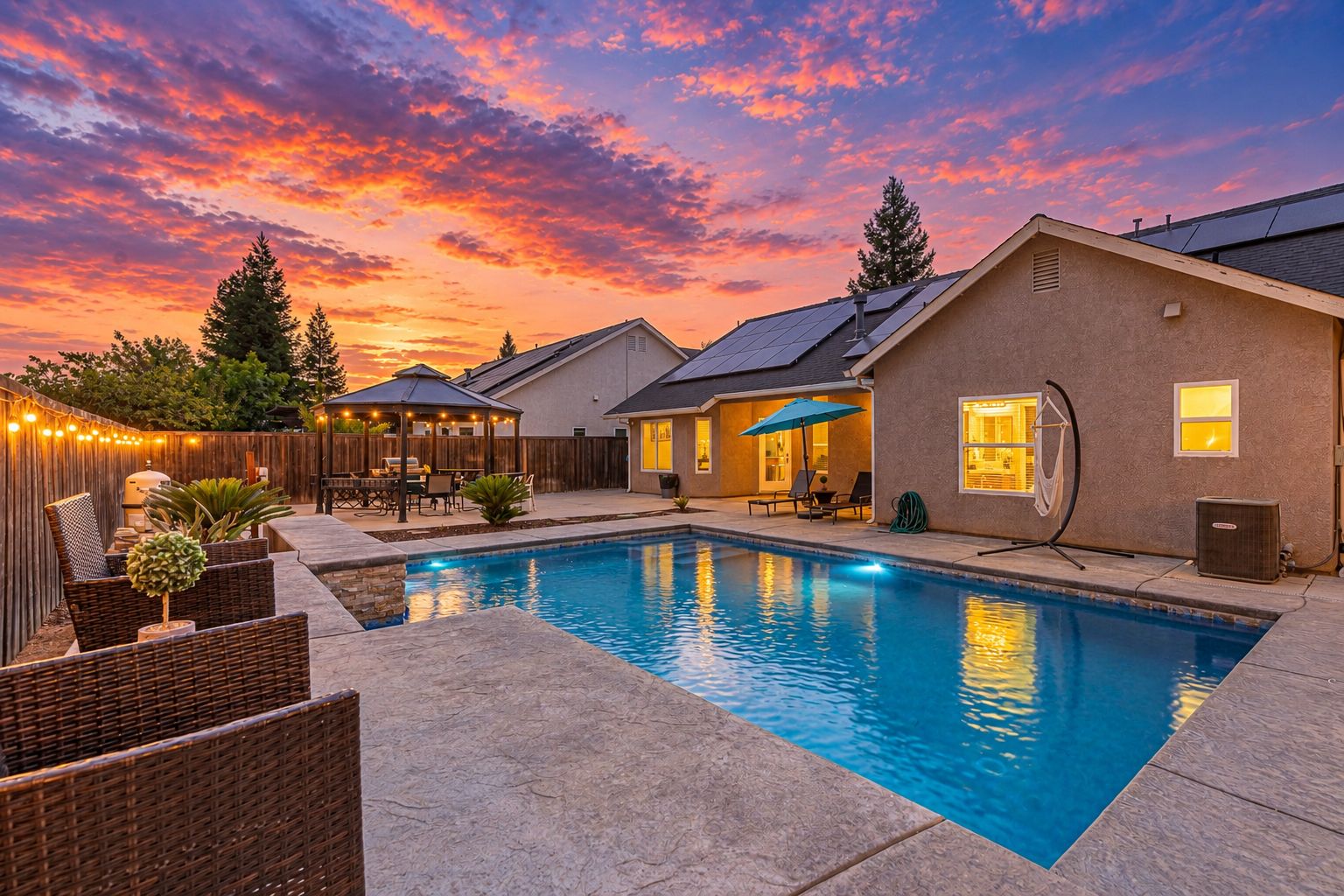 A backyard with a swimming pool, outdoor furniture, and a covered patio area.