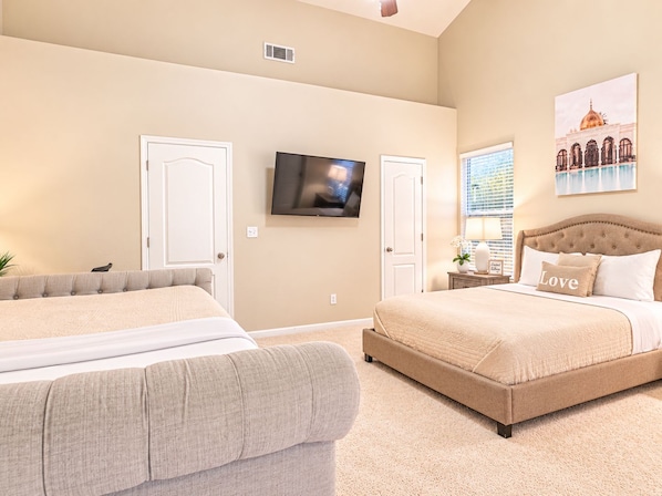 Quarto de hotel com duas camas, televisão, janela com persianas e um quadro na parede.
