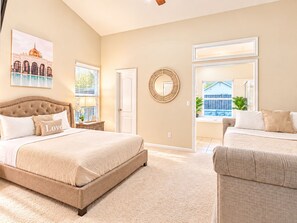 A bedroom with a large bed, a smaller sofa, a bedside table with a lamp, and a view of the outside. - Beautiful home W/Pool Close to National Parks. (Fresno)