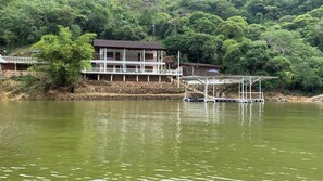 Enjoy serene lakeside views from the balcony of this tranquil retreat, surrounded by lush greenery and a dock for boat access.