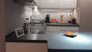 A modern kitchen with a stainless steel sink, a dish rack, and a bowl of fruit on the counter. - Lake View Apartment (Qarku i Tiranës)