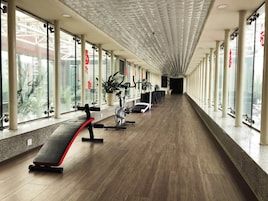Un gimnasio con equipo de ejercicio, ventanas amplias y un techo con diseño geométrico.